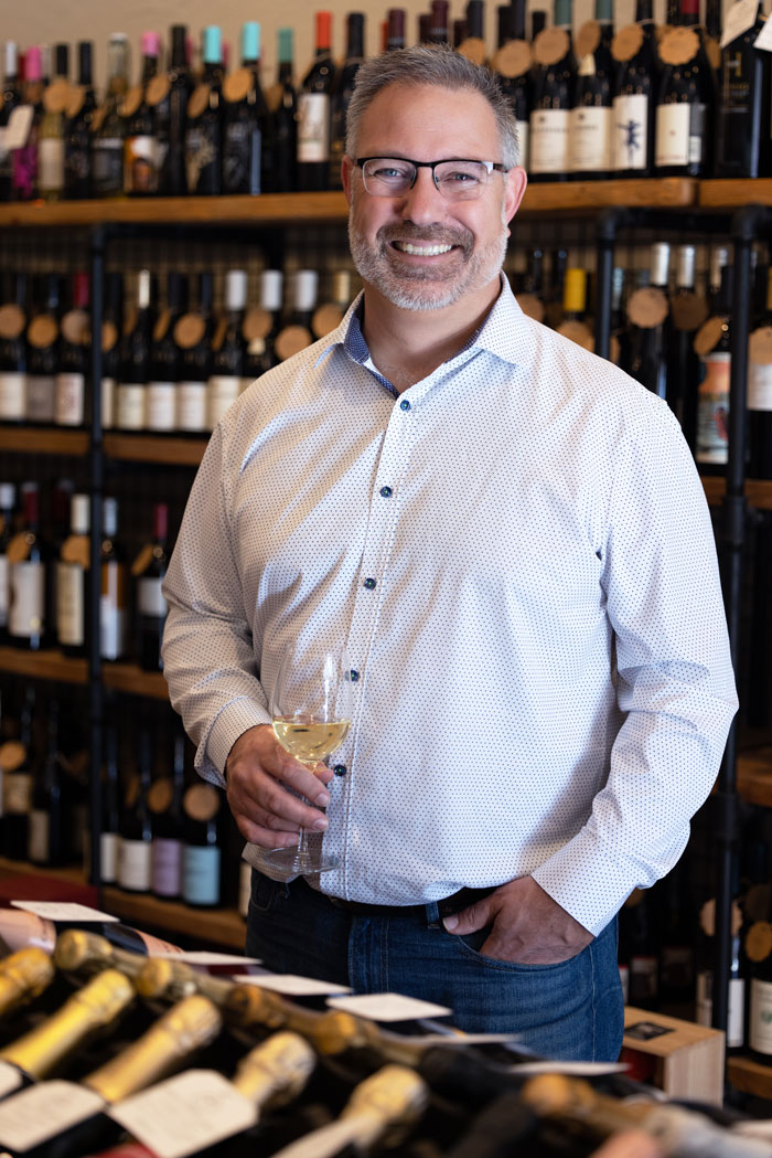neil grant owner smiling holding a glass of wine